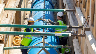 copyright: Wiener Wasser/Rauchenberger Two men in safety clothing work on a large blue pipe