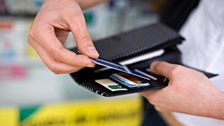 Eine Person steckt eine Bankomat- oder Kreditkarten in ein Geldbörsel.
