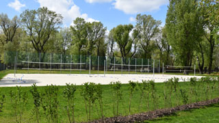 3 Volleyballplätze nebeneinander, rundherum Wiese und Bäume