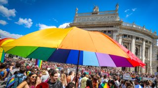 Menschenmenge hinter einem Regenbogen-Schirm