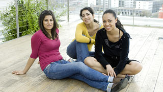 Drei junge Frauen auf einer Aussichtsplattform, im Hintergrund Stadtpanorama