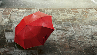 Roter Regenschirm auf Kopfsteinpflaster