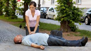 Frau leistet Erste Hilfe bei einem auf der Straße liegenden Mann