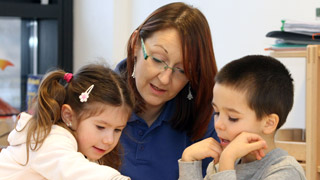 Eine Pädagogin beschäftigt sich mit einem Buben und einem Mädchen