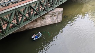 Zwei Mnner in Schlauchboot bringen Laichbrsten unter Brcke aus