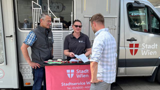 Mitarbeiterin und Mitarbeiter des Stadtservice im Gesprch mit Brger*innen, im Hintergrund der Stadtservice Bus