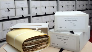 Archivmaterial in Schutzumschlag, daneben zwei Archivschachteln