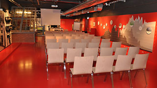 Roter Seminarraum mit Stühlen und Leinwand