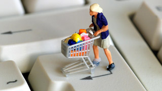 Eine Figur mit Einkaufswagen auf einer Tastatur