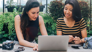 2 Frauen sitzen vor einem Laptop