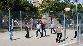 A group of teenagers are playing beachvolleyball.