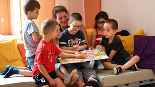 Eine Lehrerin liest sechs Kindern aus einem Buch vor