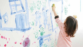 Mädchen bemalt mit den Händen eine Wand.