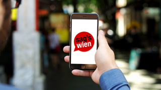Person mit "Sag's Wien"-App am Smartphone