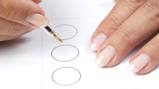 A woman’s hands holding a pen to fill in a ballot pape