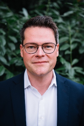 Porträt eines Mannes, Stadtrat Jürgen Czernohorszky, mit Brille in dunklem Sakko und weißem Hemd, im Hintergrund grüne Blätter. Copyright: Ingo Pertramer