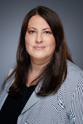 Porträt einer Frau, Vizebürgermeisterin Kathrin Gaál, mit dunklem Haar, dunkelblauem Blazer und weißem Oberteil. Im Hintergrund sind moderne, bunt gestaltete Wohngebäude zu sehen. Copyright: Stadt Wien/David Bohmann