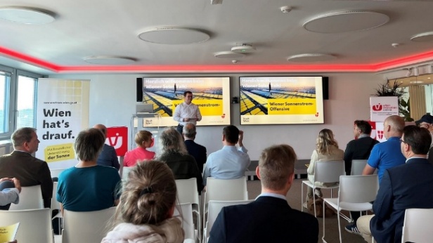 Vortragssituation in einem Konferenzraum: Eine Person spricht vor Publikum, auf zwei Bildschirmen ist eine Präsentation zur „Wiener Sonnenstrom-Offensive“ zu sehen. Copyright: Stadt Wien