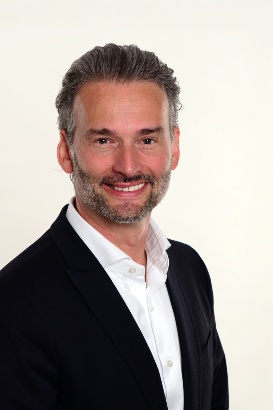 Porträt eines Mannes, Bernhard Jarolim, im dunklen Sakko und weißem Hemd, der in die Kamera lächelt. Der Hintergrund ist hell und neutral. Copyright: Stadt Wien