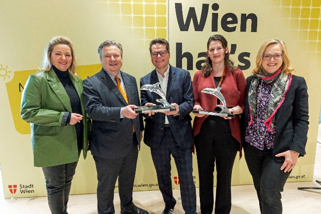 Bürgermeister Ludwig, Stadtrat Czernohorszky und Programmleiterin der MA 20 stehen gemeinsam mit den Geschäftsführerinnen der Kommunikationsagenturen Grayling und Kraftwerk vor einer gelben Wand mit dem Schriftzug „Wien hat’s drauf“. Zwei der Personen halten silberne Delphin-Trophäen in den Händen. Copyright: Stadt Wien/Bubu Dujmic