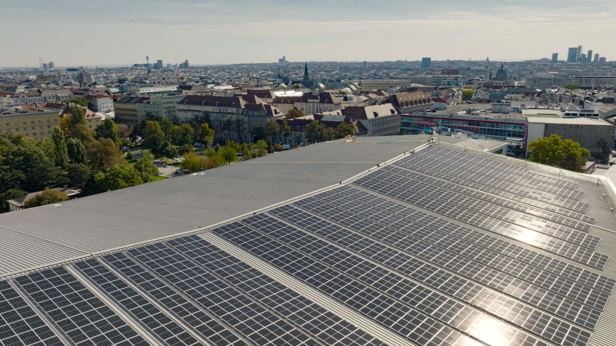 Kapitelbild: Drohnenaufnahme über dem Dach der Wiener Stadthalle mit Reflexionen der Sonne an der PV-Anlage. Copyright: MXR