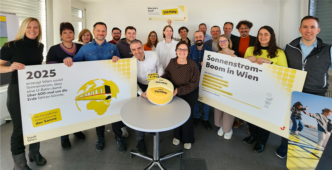 Gruppenfoto mit Mitarbeitenden der Wiener Sonnenstrom-Offensive. Mehrere Personen halten große Schilder mit Informationen zum Sonnenstrom-Boom in Wien und einem Zielwert von 250 MWp. Copyright: Stadt Wien