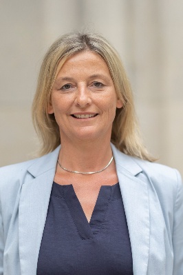 Porträt einer Frau, Beatrix Rauscher, mit blonden Haaren, hellblauem Blazer und dunkelblauer Bluse vor neutralem Hintergrund. Copyright: Stadt Wien/Bubu Dujmic