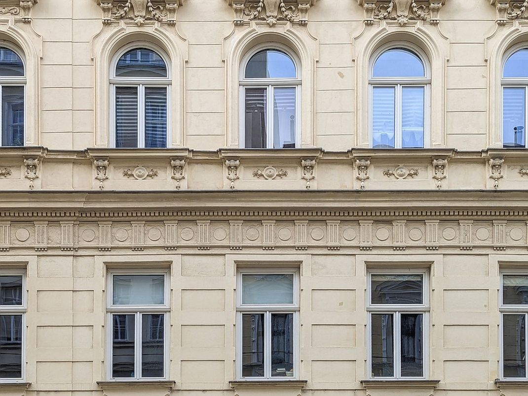 Dekorierte Gründerzeitfassade. Fenstertausch auf einschichtige Rahmenstockfenster mit schlankem Rahmen, historisch profiliertem Kämpfer und charakteristischer T-Teilung, um das historische Erscheinungsbild nachzuempfinden.