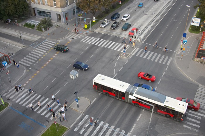 Von-Oben-Aufnahme einer belebten Kreuzung mit Fußgängern, Autos und öffentlichen Verkehrsmittel