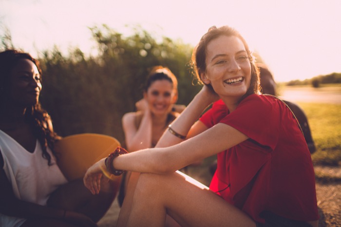 Im Grünen: Eine junge Frau lächelt in Richtung Kamera während eines Sonnenuntergangs