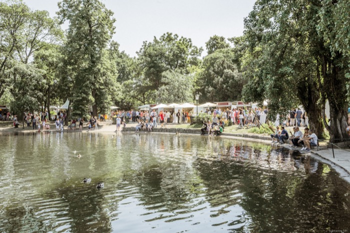 Jüngere und ältere Menschen an einem Teich in einem Park