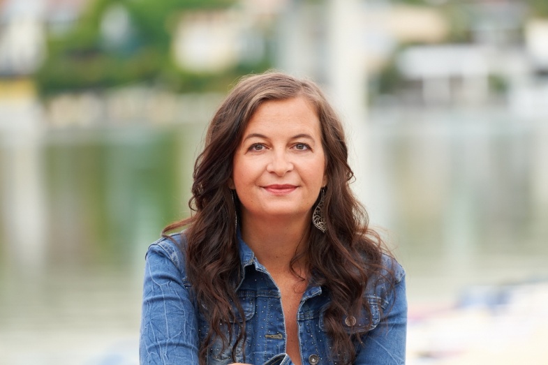 Formal portrait of executive City Councillor Mag. Ulli Sima: She is wearing a denim jacket and has long brown hair.
