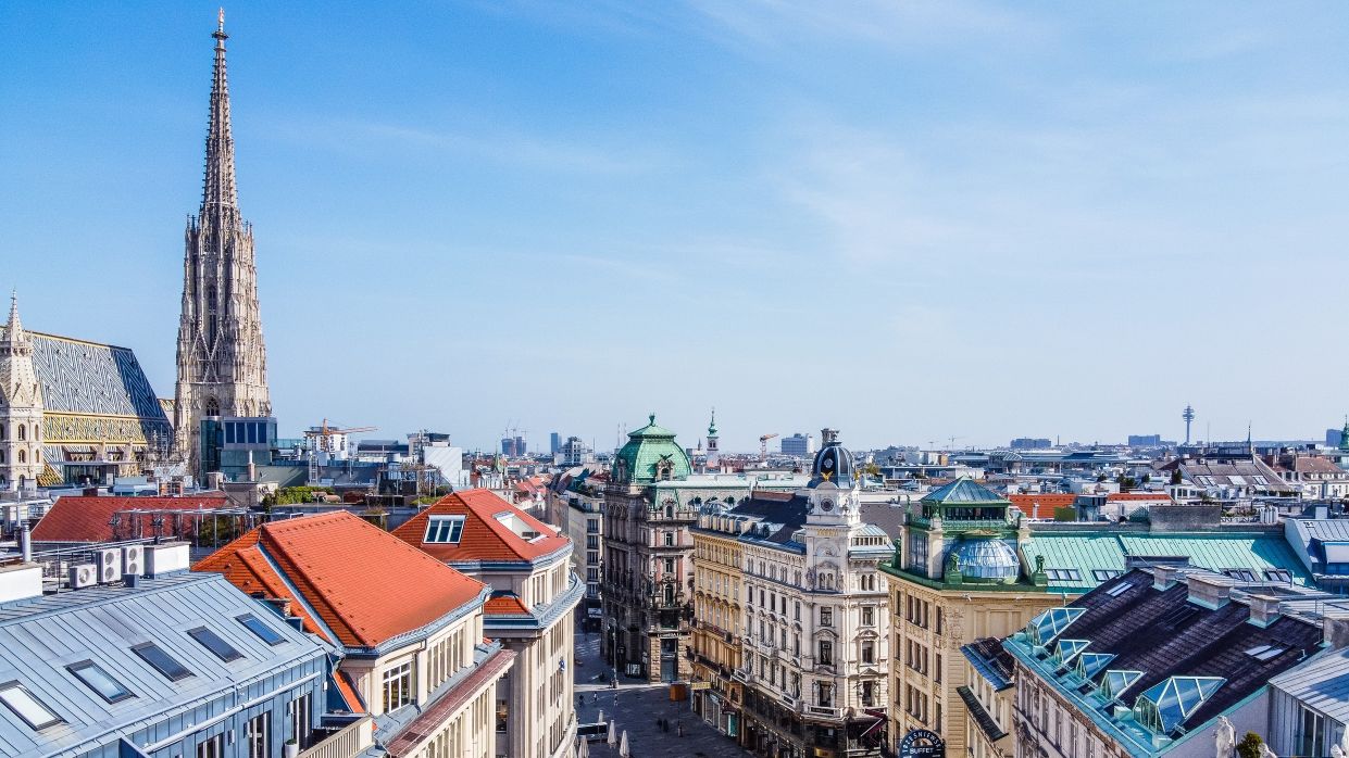 Kapitelbild: Blick über Wien, auf der linken Seite ist der Stephansdom erkennbar, zentral im Bild ist eine Straße zu sehen. 