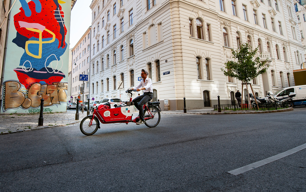 Mann mit Lastenfahrrad auf einer Straße in Wien