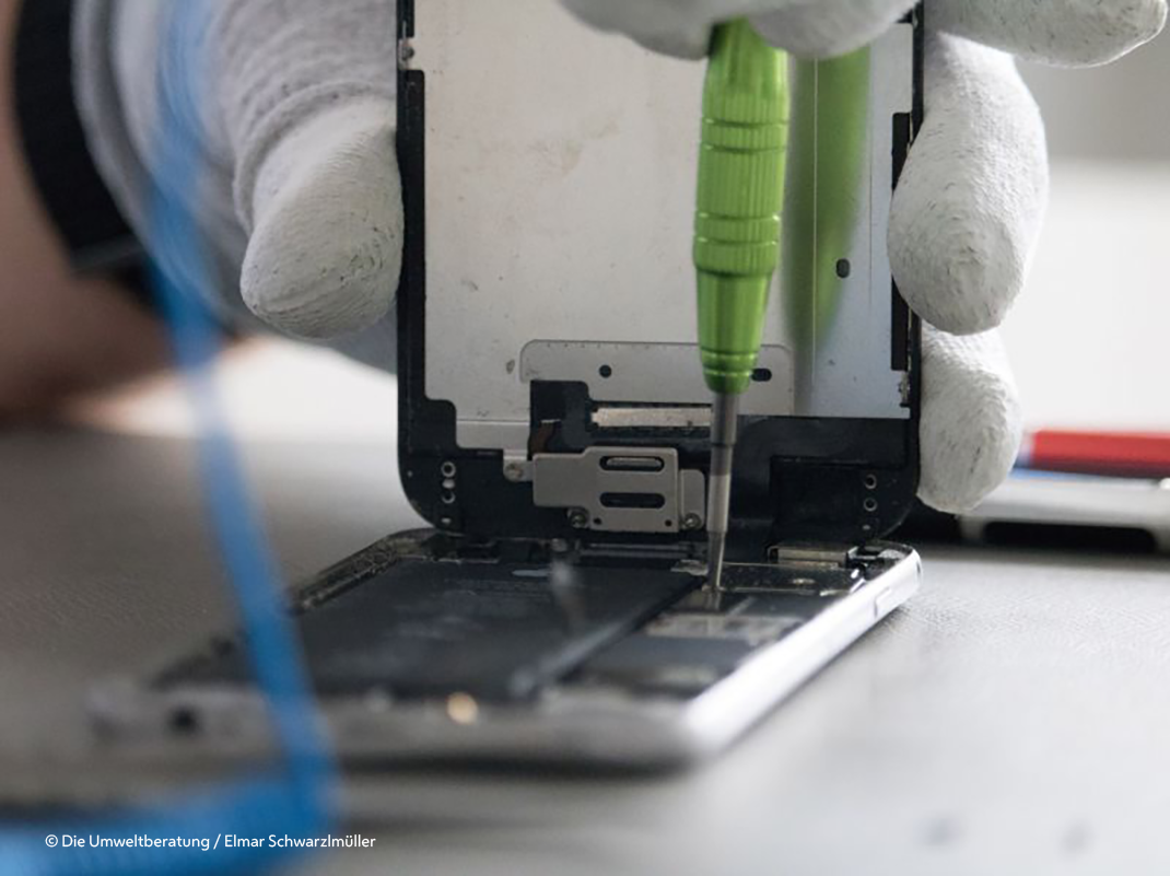 Detailfoto einer Handyreparatur mit Händen und Schraubenzieher