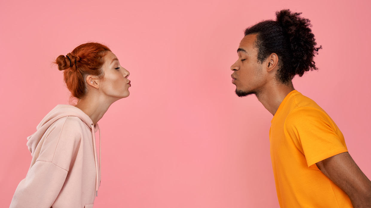 Kapitelbild: Foto von zwei Personen vor einfarbig rosa Hintergrund, die sich mit geschlossenen Augen und vorgebeugtem Oberkörper zum Küssen nähern. © istockphoto.com