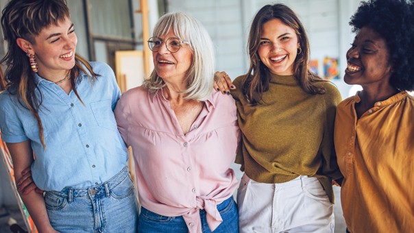 Kapitelbild: Vier Frauen unterschiedlichen Alters stehen lachend nebeneinander in einem hellen Raum und zeigen Zusammenhalt und Freund*innenschaft. © istockphoto