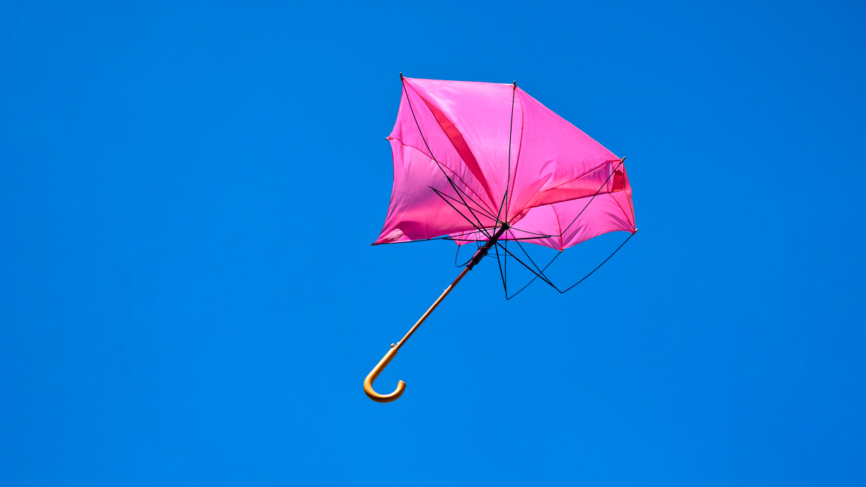 Kapitelbild: Fotografie eines geöffneten und kaputten pinkfarbenen Regenschirms vor klarem, blauem Himmel. © istockphoto.com