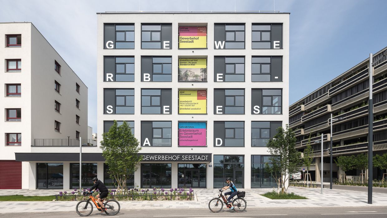 Kapitelbild: modernes Gebäude mit Buchstaben in jedem Fenster die das Wort „GEWERBE-SEESTADT“ bilden