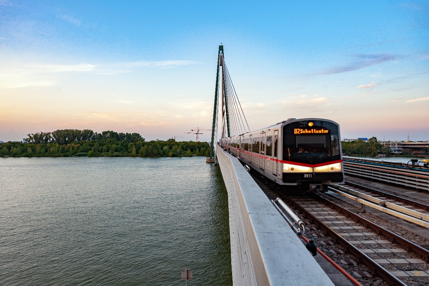 Ein Zug der U-Bahn-Linie U2 überquert die Donau in der Dämmerung.