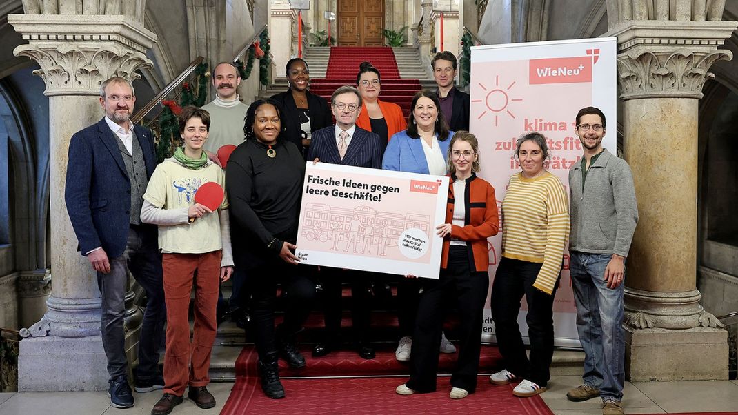 Group photo of the winners of the Grätzlinitiative competition; the women and men are standing on a flight of steps at the Town Hall. Two of the winners, standing in the centre, are holding a sign that reads ‘Fresh ideas to combat empty shops!’. Deputy Mayor Gaál and Gerhard Hirczi, head of the Economic Development Agency, are standing behind the young people. 