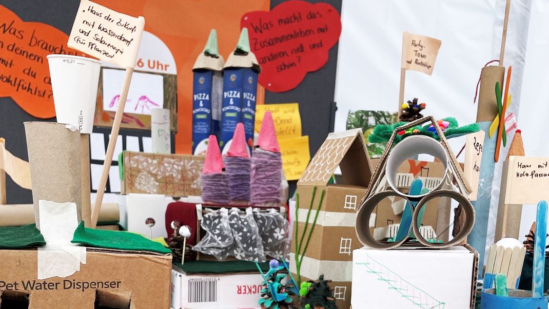 A colourful children’s craft project using cardboard boxes, yarn and paper, depicting a town with a street running through the centre.