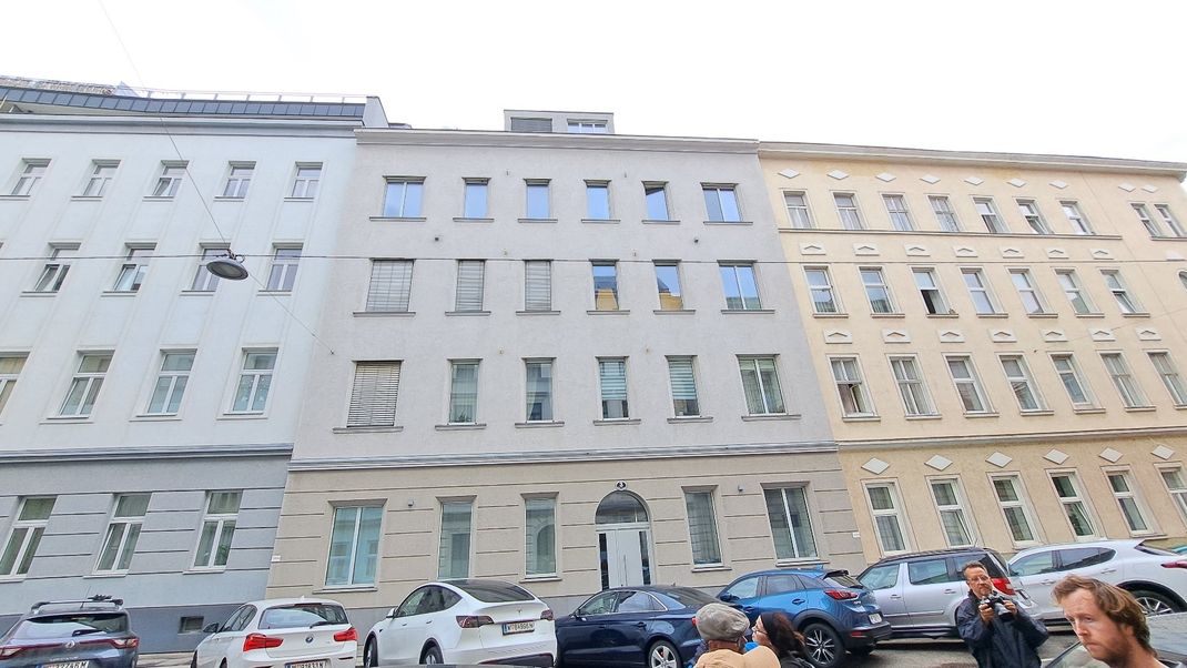 A row of three Gründerzeit apartment blocks, each with four storeys. On the left and right, the windows retain their original design; in the middle is the building with single-glazed windows.