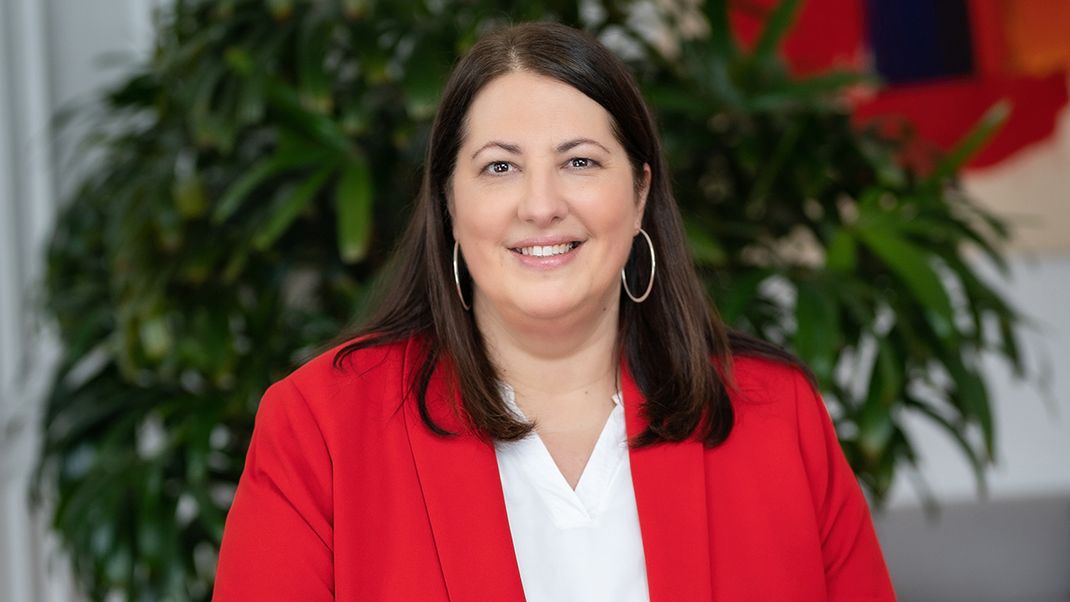 A portrait photograph of Kathrin Gaál wearing a red jacket and a white blouse.