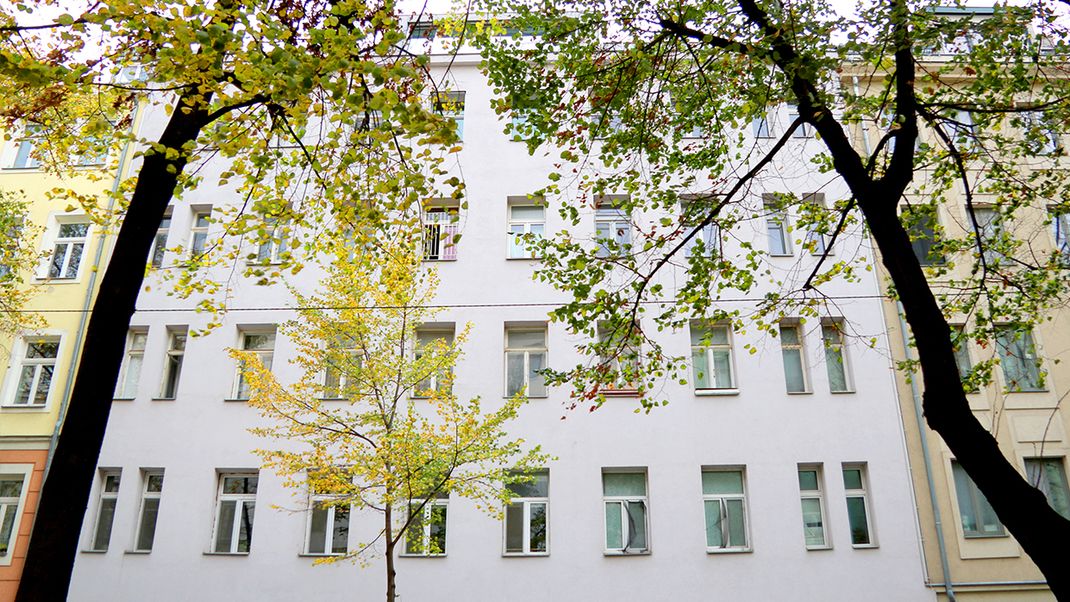 Außenansicht des gründerzeitlichen Hauses in der Ybbsstraße 6. Vier Stockwerke, weiße Fassade und hohe Fenstern. Davor drei Bäume mit grünem Laub.