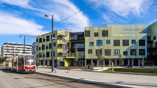 Fassadenansicht Bildungscampus, davor fährt eine Straßenbahn