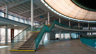 runder Innenraum, großzügige Treppe führt auf Galerie, türkisfärbiges Geländer