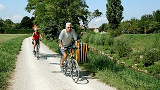 Zwei ltere Menschen radeln entlang des Radwegs am Liesingbach