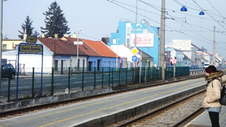 Person am Bahnsteig der Station Vösendorf-Siebenhirten, im Hintergrund Industriegebiet