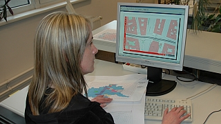 Mitarbeiterin blickt auf Bildschirm, auf dem Kartenausschnitt dargestellt ist.